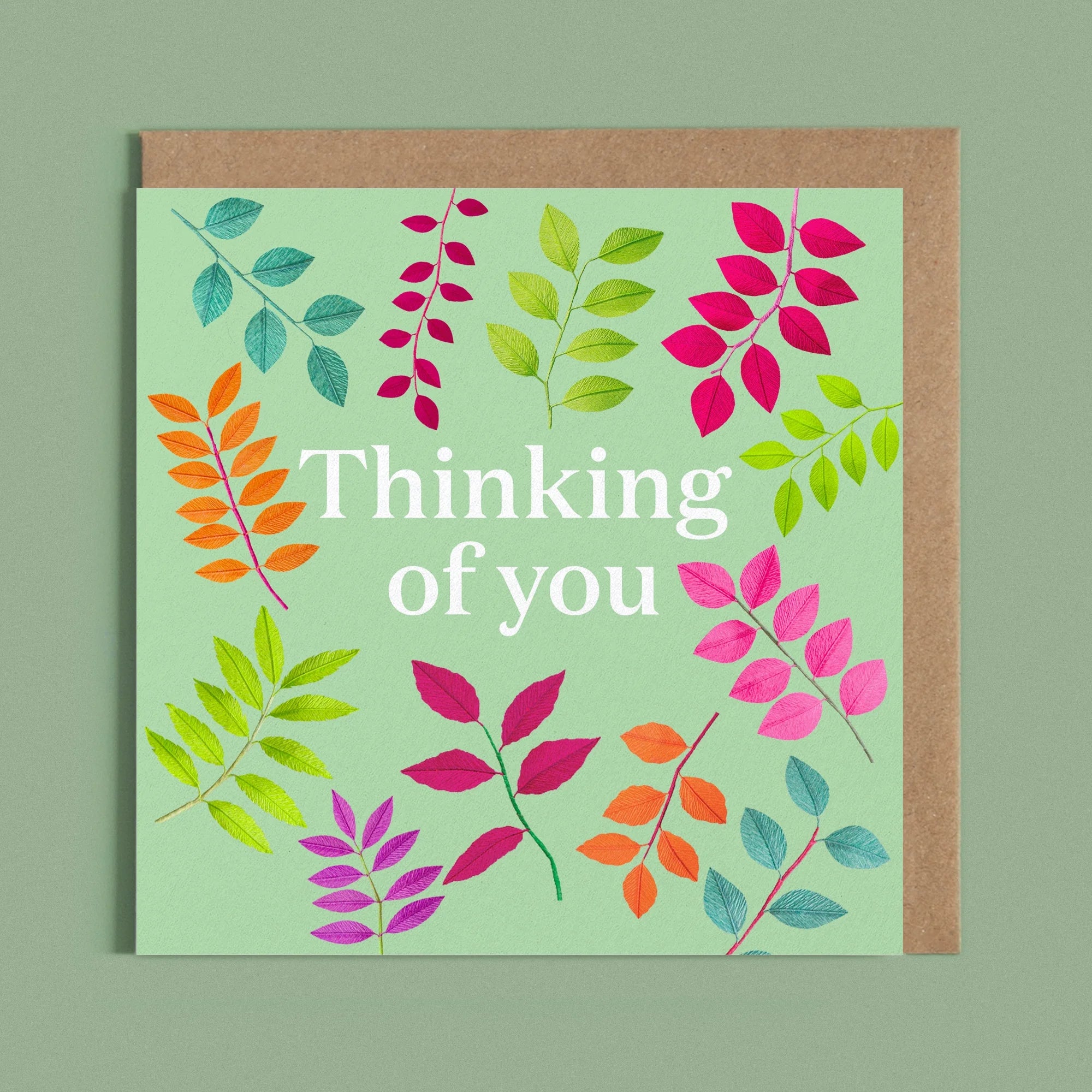 Greeting card with the message 'thinking of you' next to a image of a handcrafted paper colourful foliage on a bright green background by paper artist Daphne Fitch.