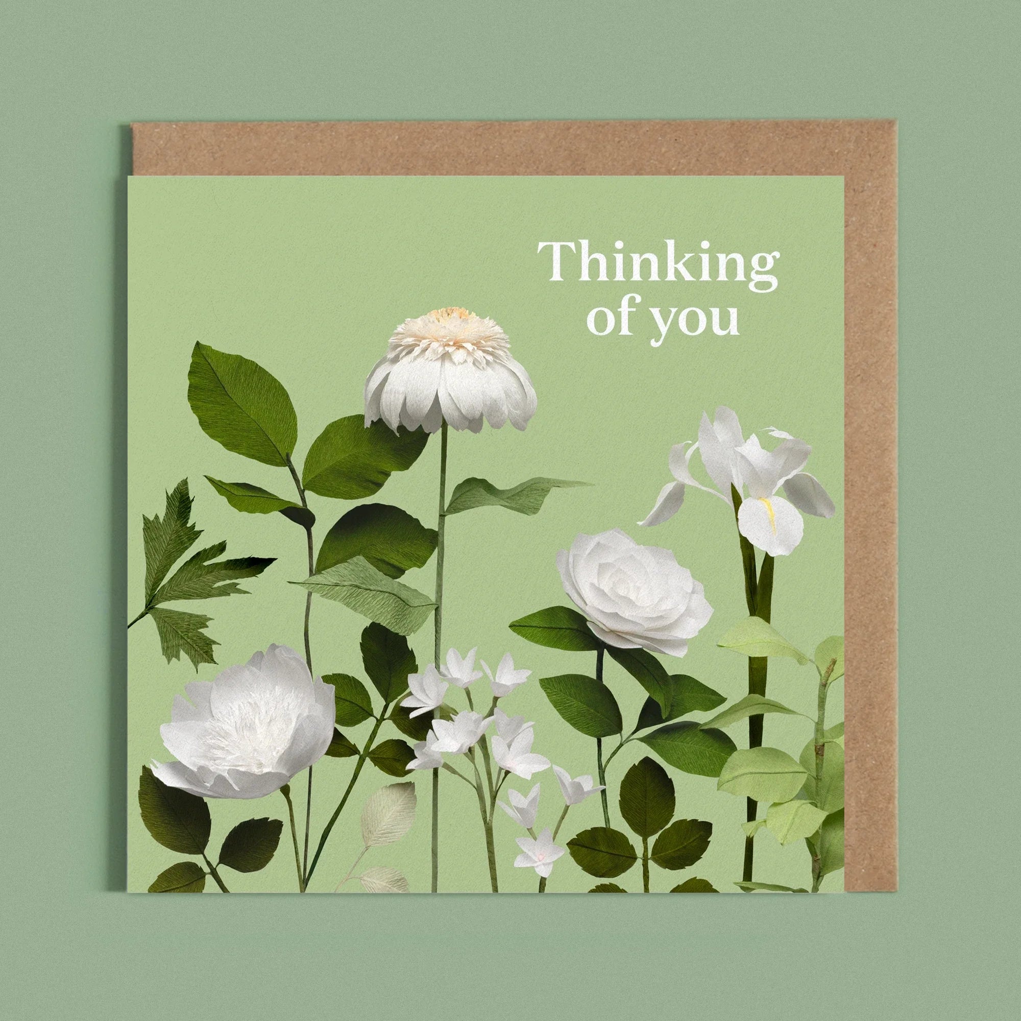 Greeting card with the message 'thinking of you' next to a image of a handcrafted paper White flowers on a bright green background by paper artist Daphne Fitch.