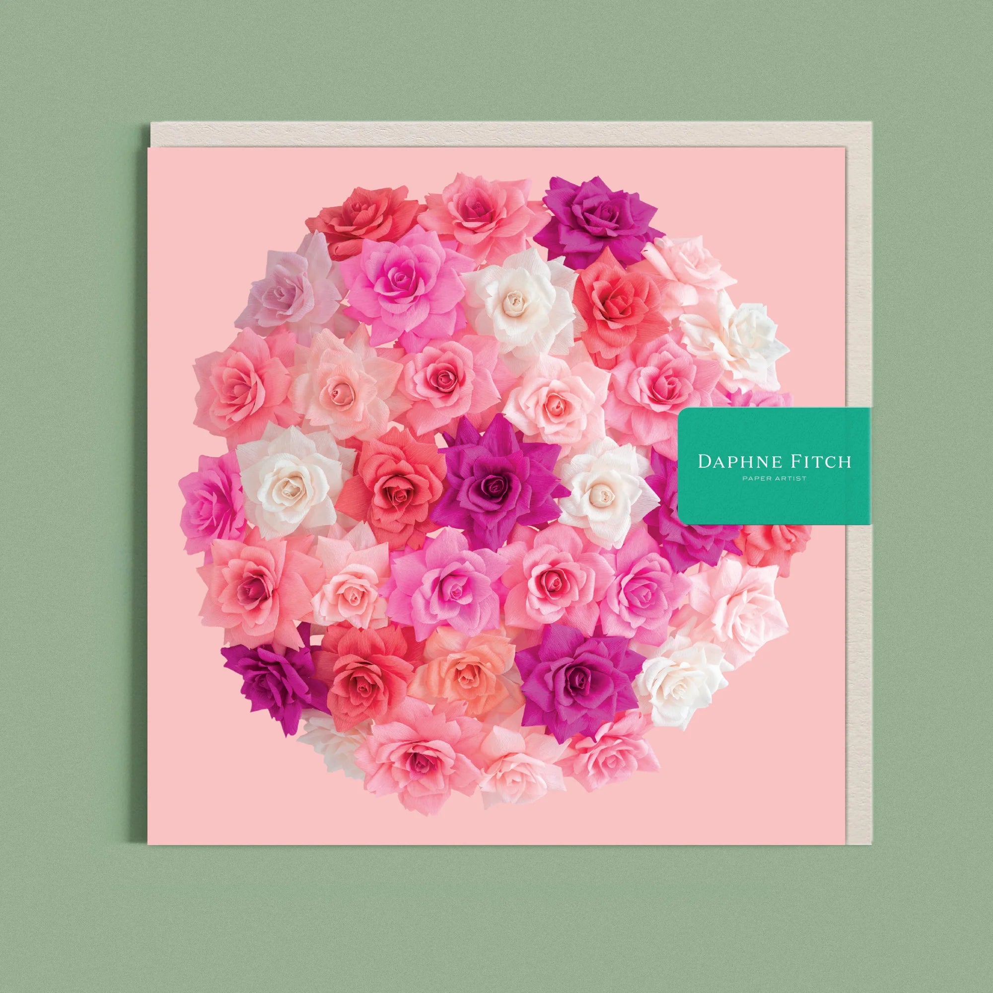 Greeting card with a image of a handcrafted paper rose bombe on a pink background by paper artist Daphne Fitch.