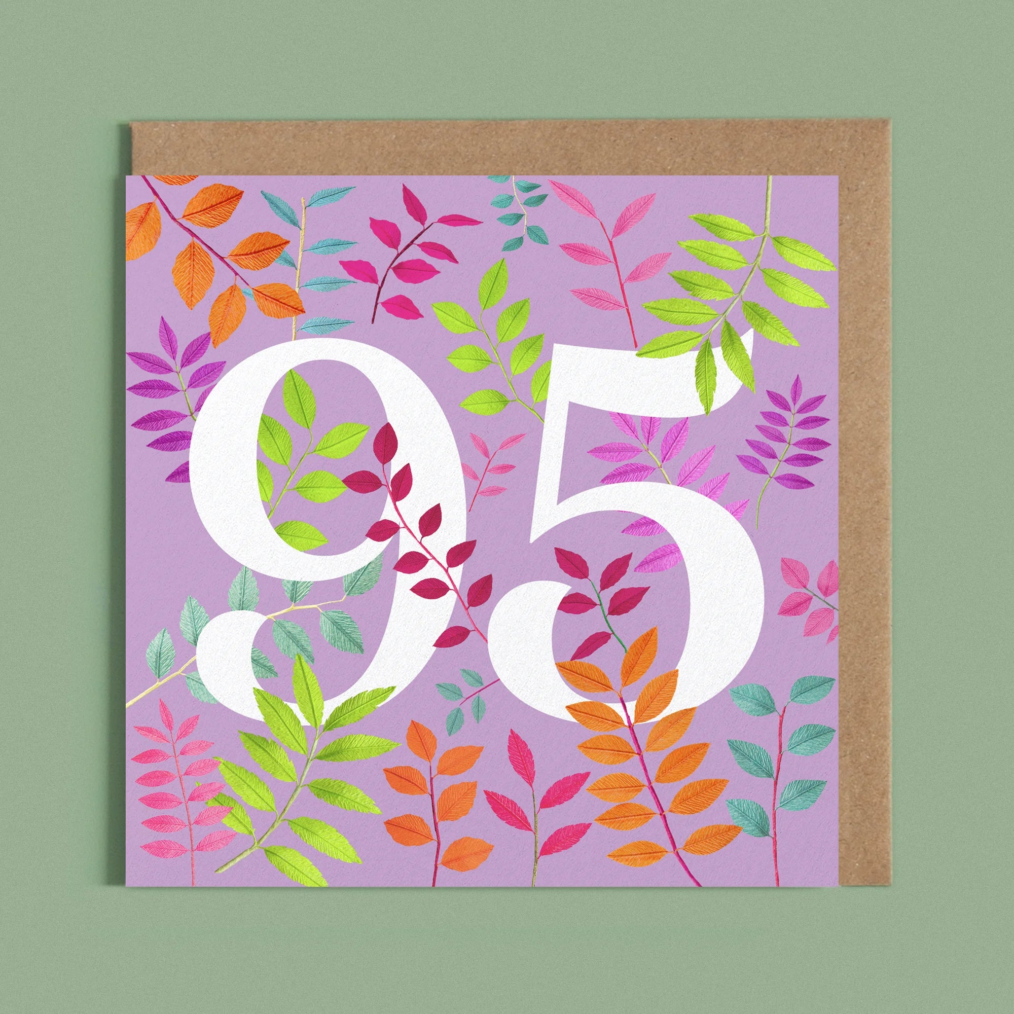Greeting card with a image of a white number 95 and colourful handcrafted paper foliage on a purple background by paper artist Daphne Fitch.