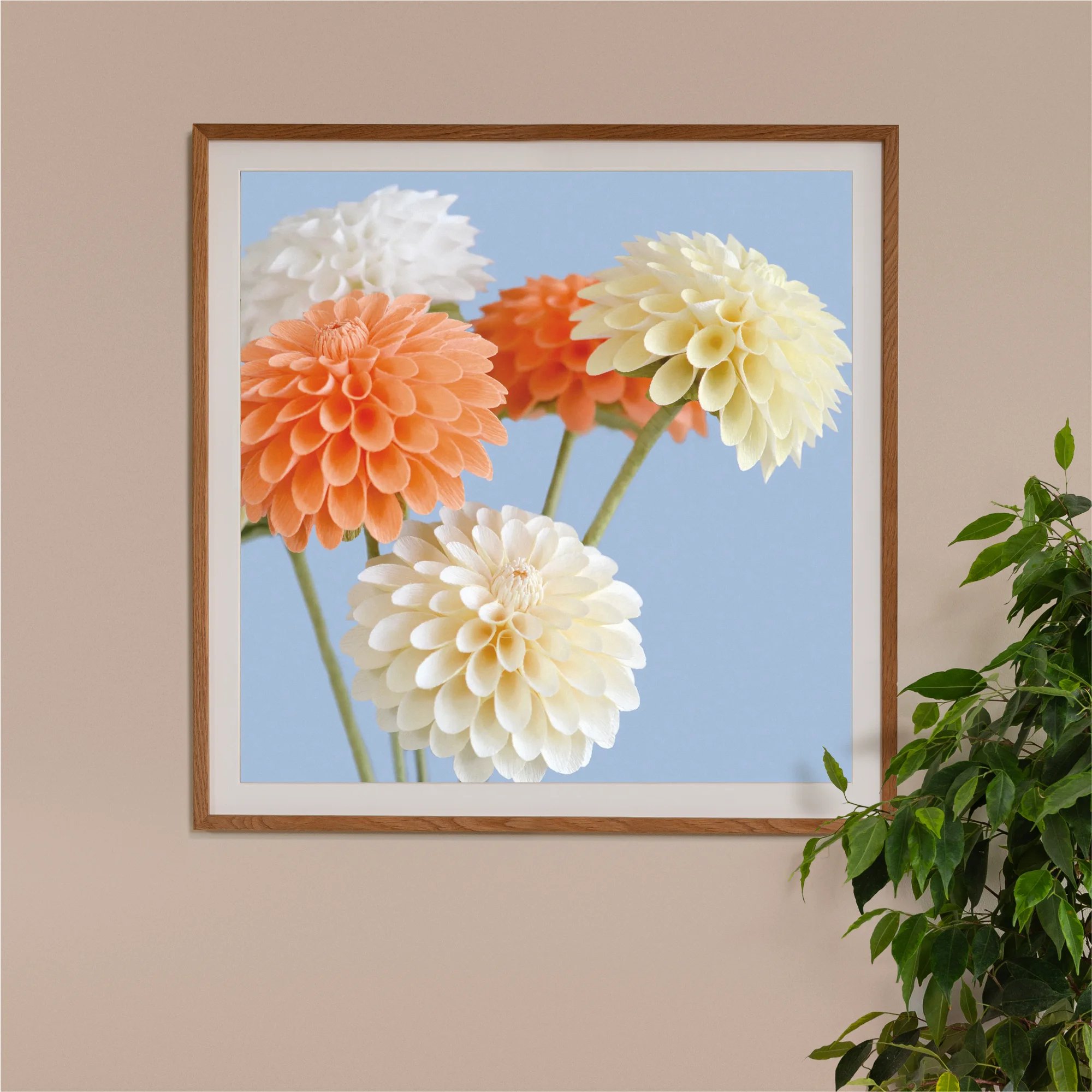 Image of framed art print on a wall, featuring handcrafted paper dahlias on a blue background. Created by paper artist Daphne Fitch.