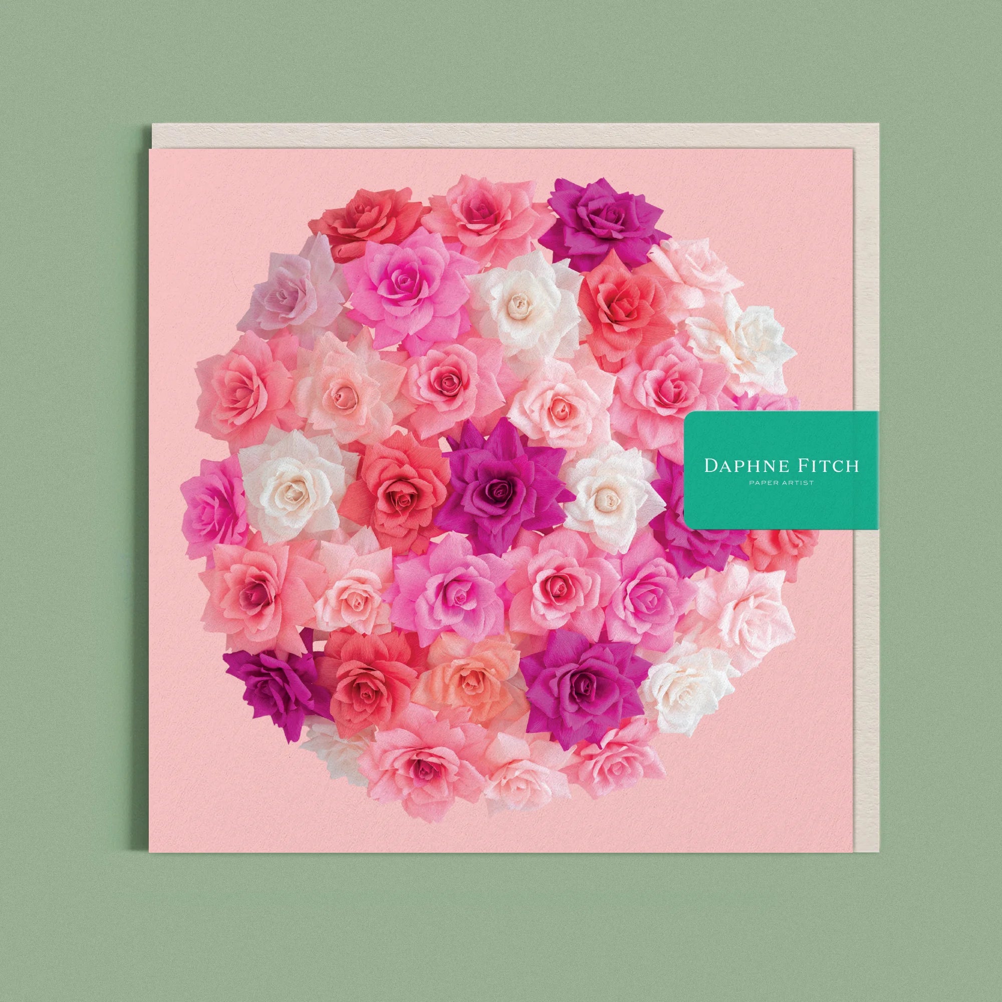 Greeting card with a image of a handcrafted paper rose bombe on a soft pink background by paper artist Daphne Fitch.