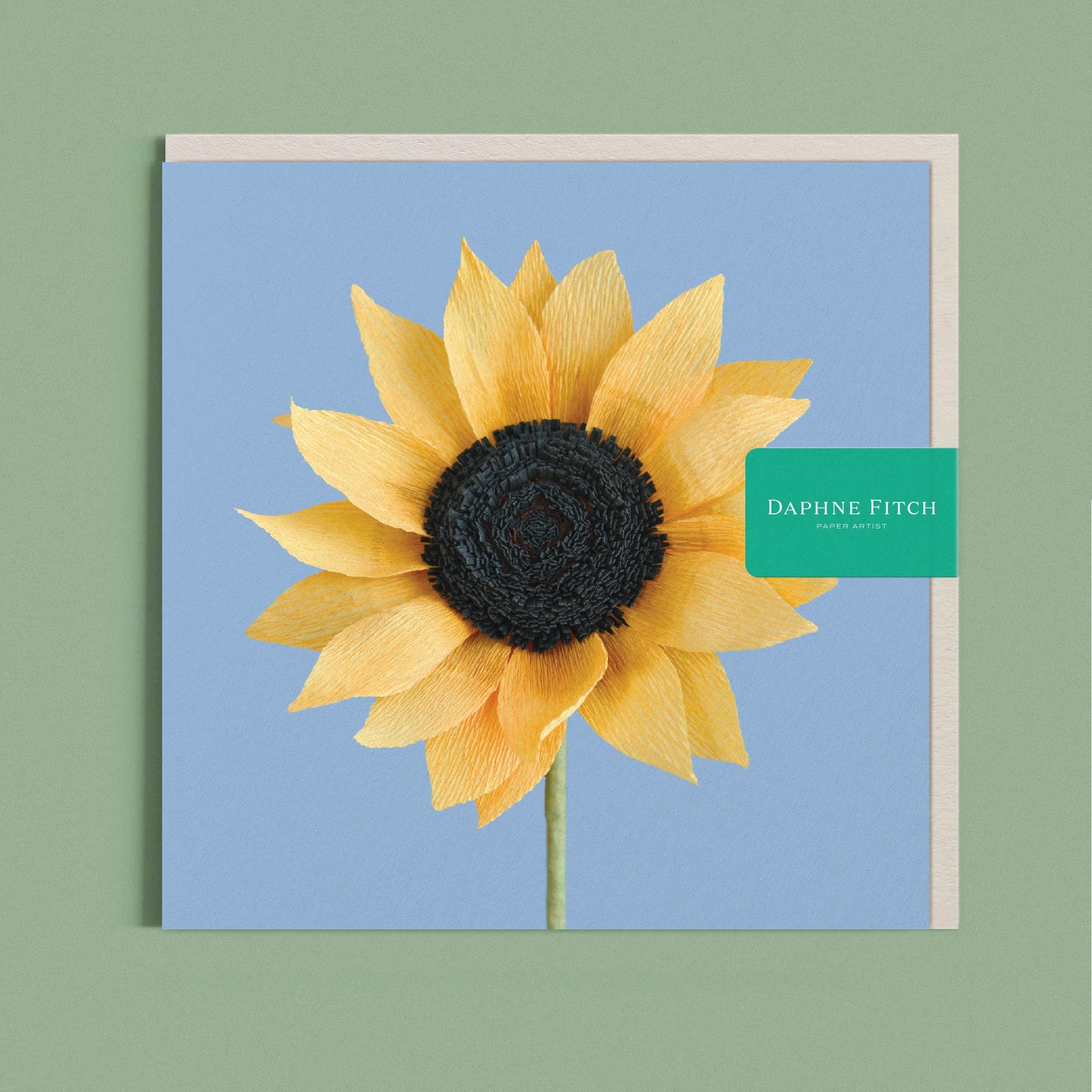 Greeting card with a image of a handcrafted paper sunflower on a light cerulean blue background by paper artist Daphne Fitch.